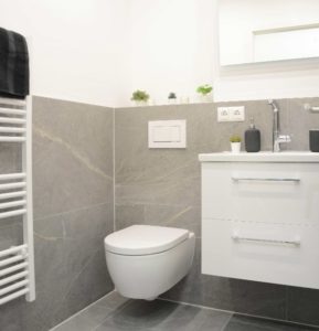 Im Bad befindet sich eine Walk-In Dusche mit einer integrierten Ablage, eine Echtglas-Duschabtrennung, eine Handtuchheizung und als Highlight zudem eine Fußbodenheizung. ANDERS CONSULTING Relocation Service München