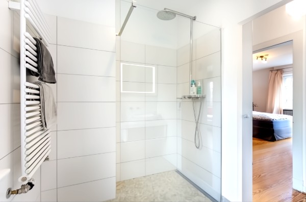 Modernes Duschbad mit bodengleicher Dusche, Handtuchheizkörper und Blick ins Schlafzimmer