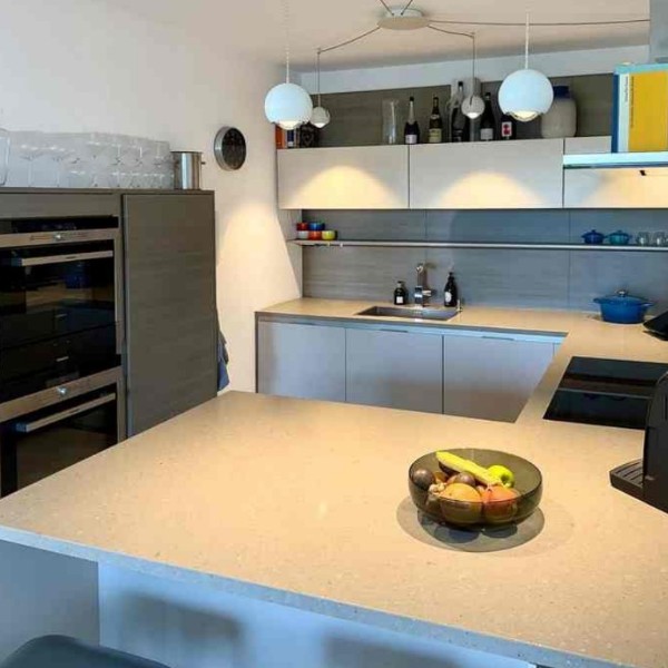 Hochwertige Einbauküche mit Kücheninsel, Fensterfront und Blick in den Wohnbereich – 4-Zimmer-Wohnung Westhafen Frankfurt