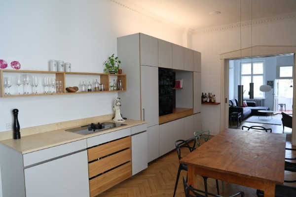 Offene Einbauküche mit Holzfronten und Blick ins Esszimmer in der möblierten 6,5-Zimmer-Altbauwohnung Berlin
