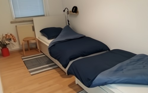 Schalzimmer mit Laminat und zwei an der Wand stehenden Betten