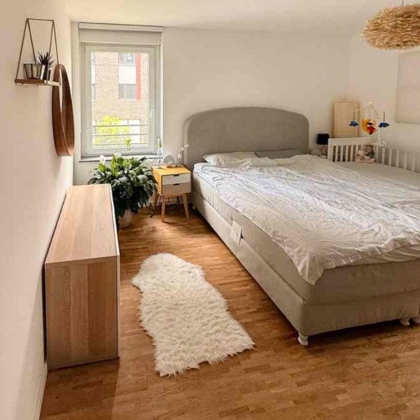 Helles Schlafzimmer mit Parkettboden, großem Fenster und Blick ins Grüne – Wohnung Westhafen Frankfurt am Main