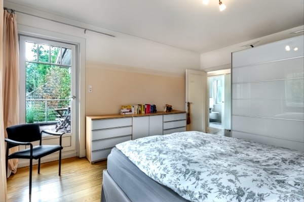 Geräumiges Schlafzimmer mit Doppelbett, Sitzecke und Balkonzugang mit Grünblick