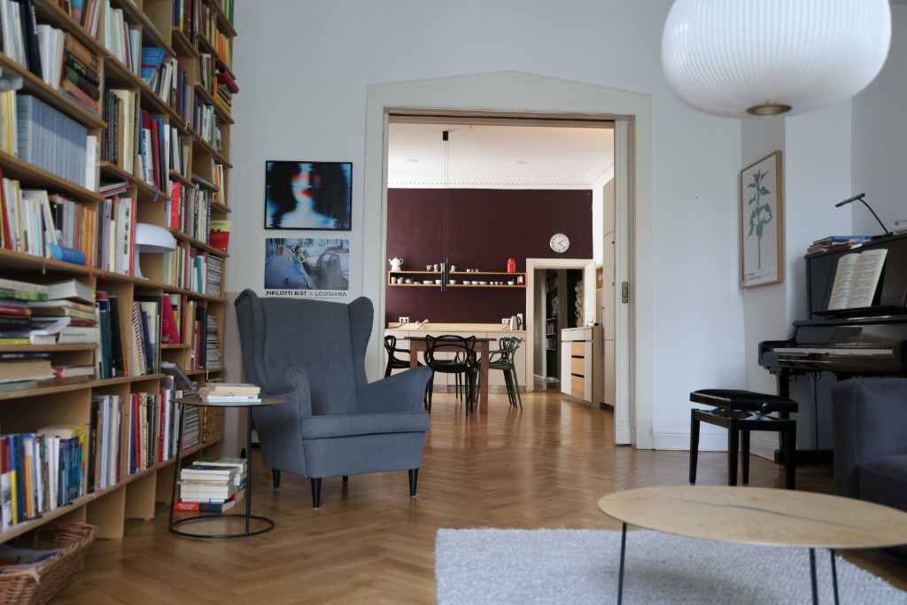 Wohnbereich mit Bücherregal, Kamin und Blick in den Essbereich der gehobenen Altbauwohnung Berlin auf Zeit