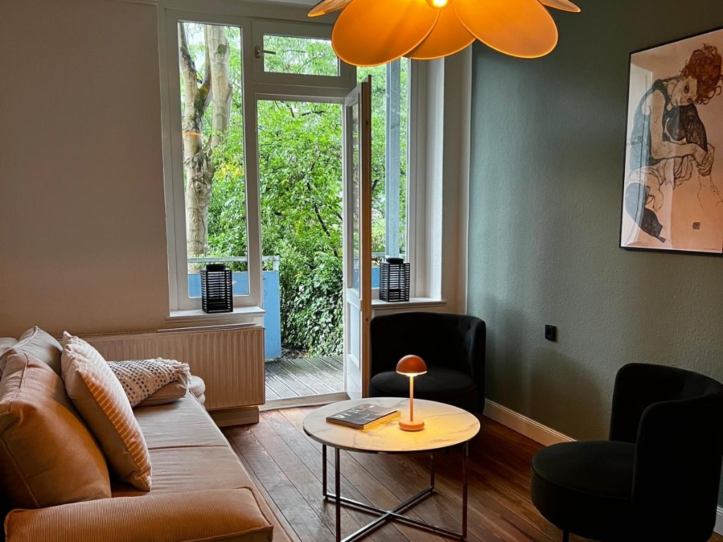Das Wohnzimmer einer Altbauwohnung im Boutique-Stil mit gemütlichen Sofa in Beige und zwei schwarzen Sesseln