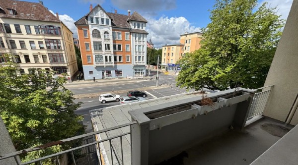 Blick vom Süd-Balkon der Wohnung Kastanienallee 68 auf die Straßenkreuzung mit Altbauten und Bäumen