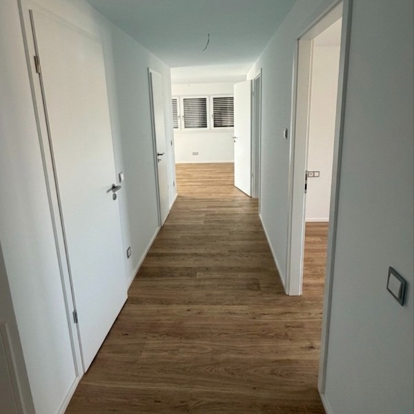 Heller Flur mit Holzboden und weißen Zimmertüren, die zu den Wohnräumen führen