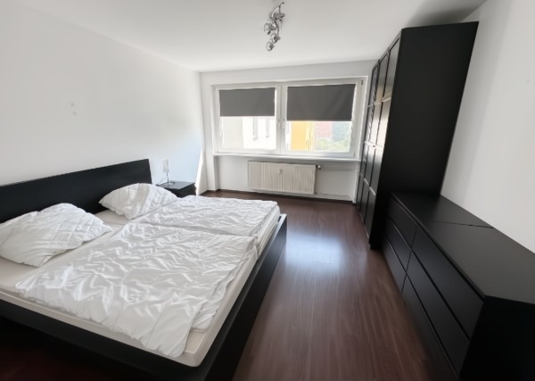 Schlafzimmer mit Doppelbett, schwarzem Kleiderschrank und Kommode